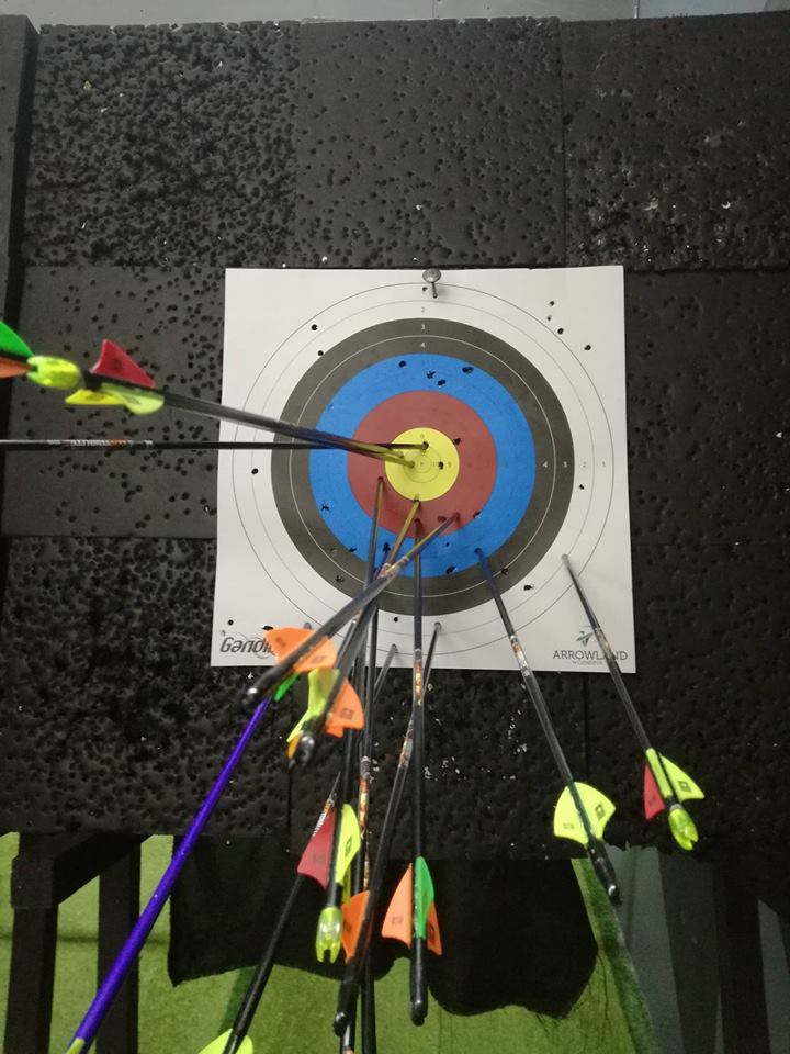 Archer aiming bow at targets inside Arrowland archery range