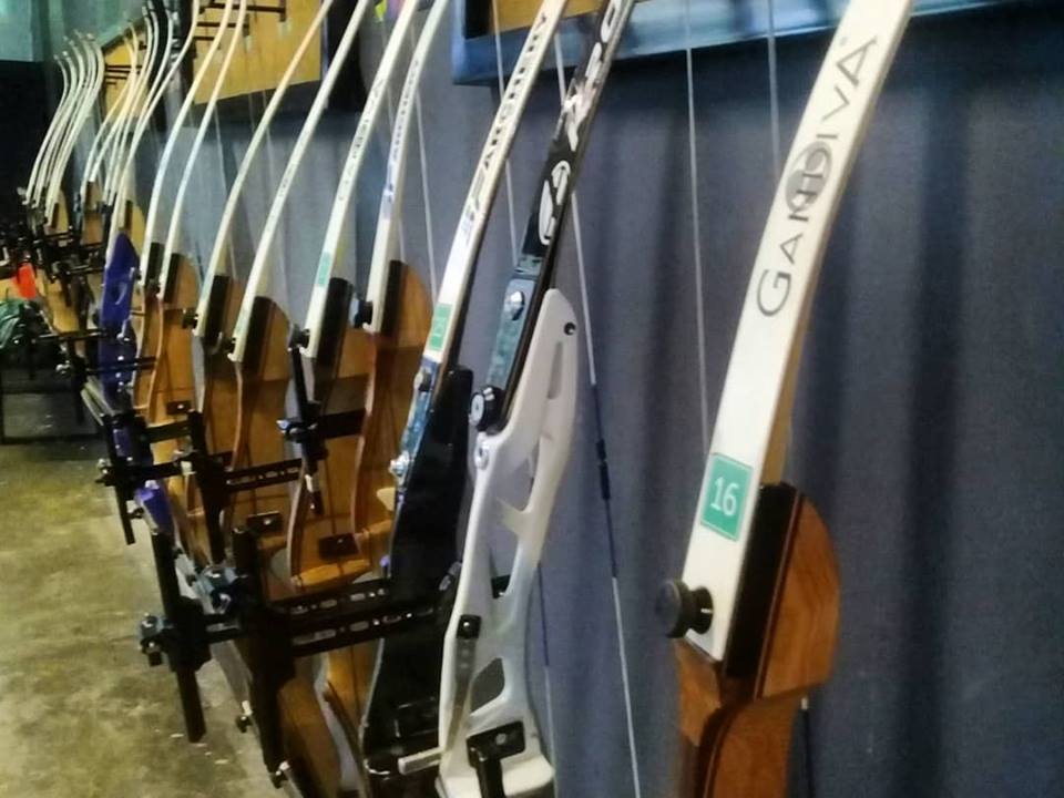 Row of Gandiva bows lined up on the equipment rack at Arrowland